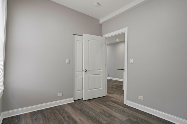 unfurnished room with dark wood finished floors and baseboards