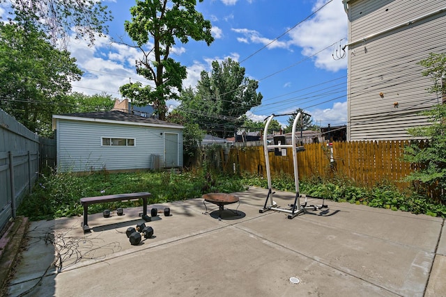 view of patio with a fenced backyard, a fire pit, and an outbuilding