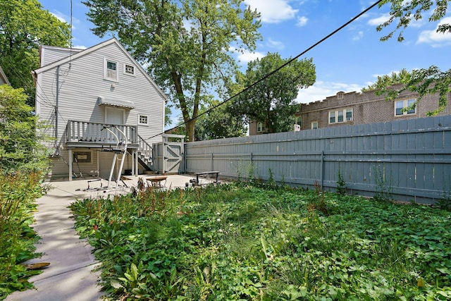 view of yard with stairs, a deck, a patio area, and a fenced backyard