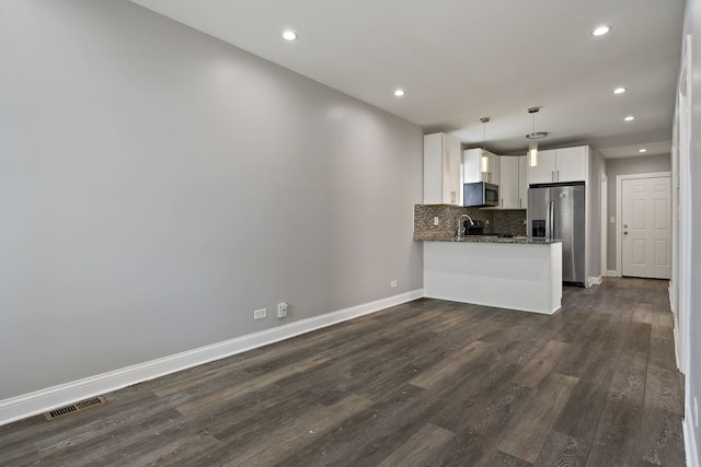 kitchen with decorative light fixtures, stainless steel appliances, white cabinets, dark stone counters, and a peninsula