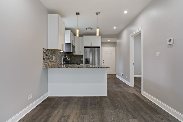 kitchen with white cabinets, dark stone counters, a peninsula, black microwave, and stainless steel refrigerator with ice dispenser