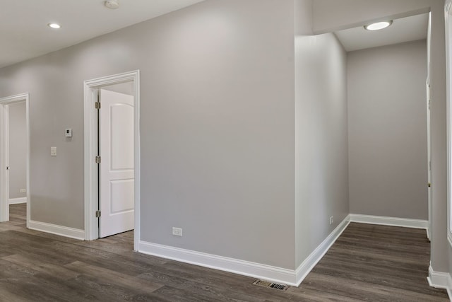 hall featuring dark wood-type flooring, visible vents, and baseboards