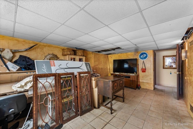 interior space with a drop ceiling and light tile patterned flooring