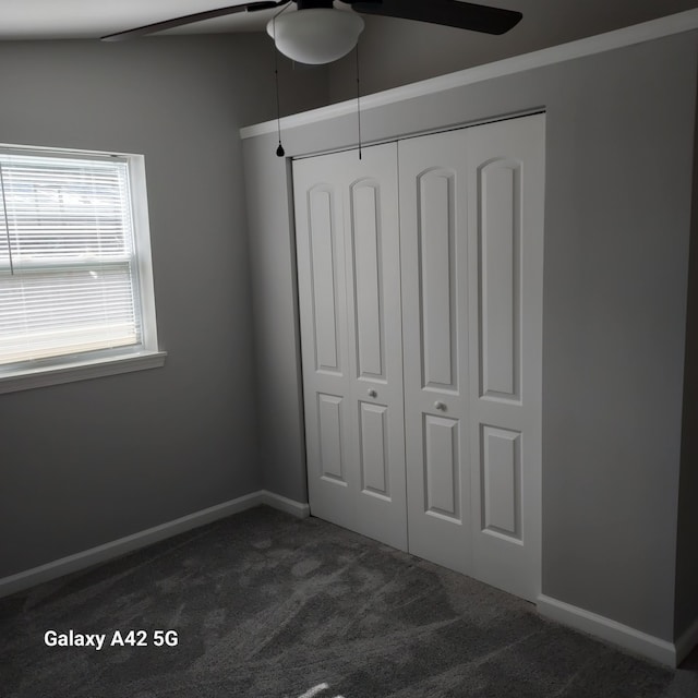 unfurnished bedroom with a closet, dark carpet, and baseboards