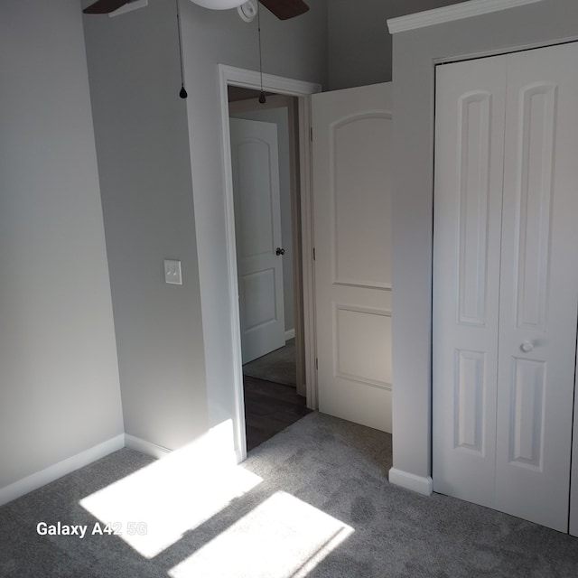 unfurnished bedroom featuring dark colored carpet, a closet, and baseboards