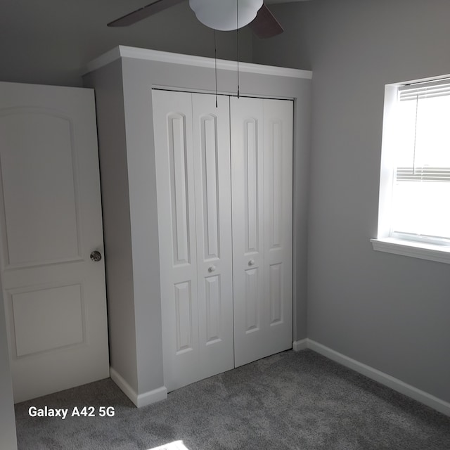 unfurnished bedroom featuring a closet, carpet, a ceiling fan, and baseboards