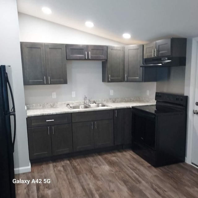 kitchen with light countertops, vaulted ceiling, a sink, under cabinet range hood, and black appliances