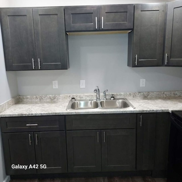 kitchen featuring black range with electric stovetop, a sink, and light stone counters