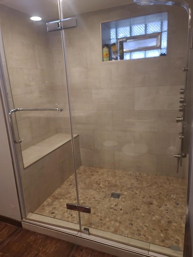 bathroom featuring wood-type flooring and a shower with shower door