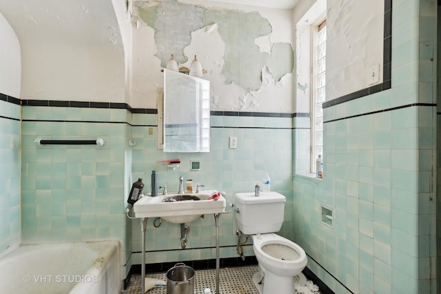 bathroom with a bathtub, toilet, tile walls, and sink