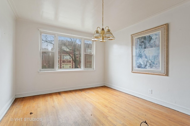 spare room featuring hardwood / wood-style floors, ornamental molding, and a chandelier