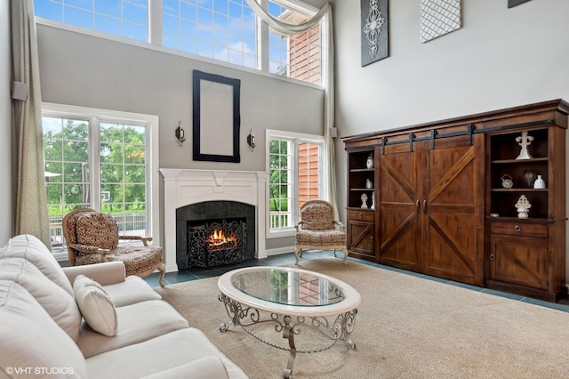 living room with a barn door, a tile fireplace, and a towering ceiling