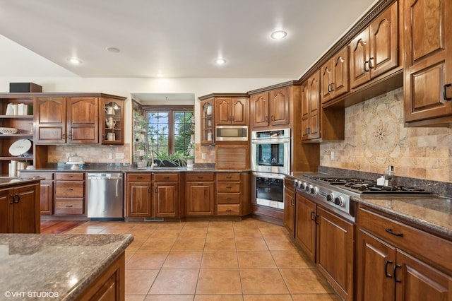 kitchen featuring light tile patterned floors, appliances with stainless steel finishes, tasteful backsplash, sink, and dark stone counters