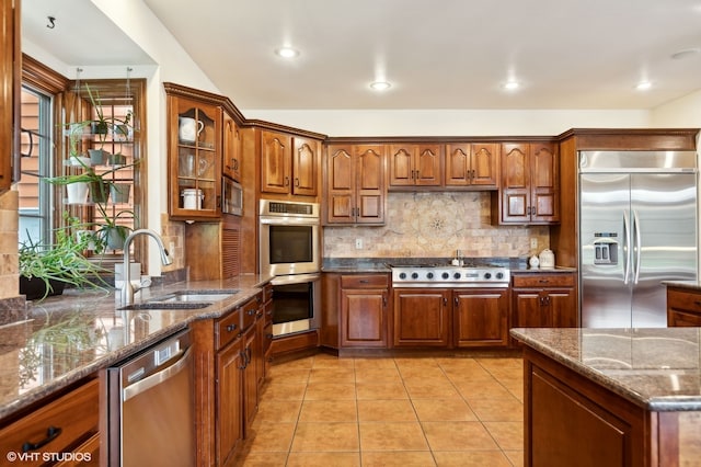 kitchen with light tile patterned floors, stainless steel appliances, sink, decorative backsplash, and stone countertops