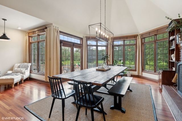 dining space with french doors, an inviting chandelier, high vaulted ceiling, and hardwood / wood-style flooring