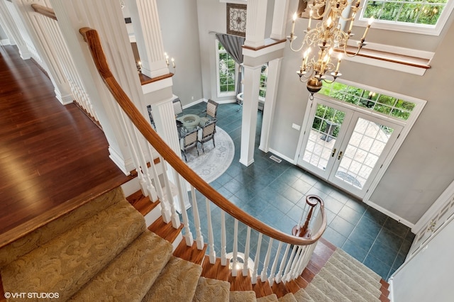 staircase with a healthy amount of sunlight, a high ceiling, a notable chandelier, and french doors