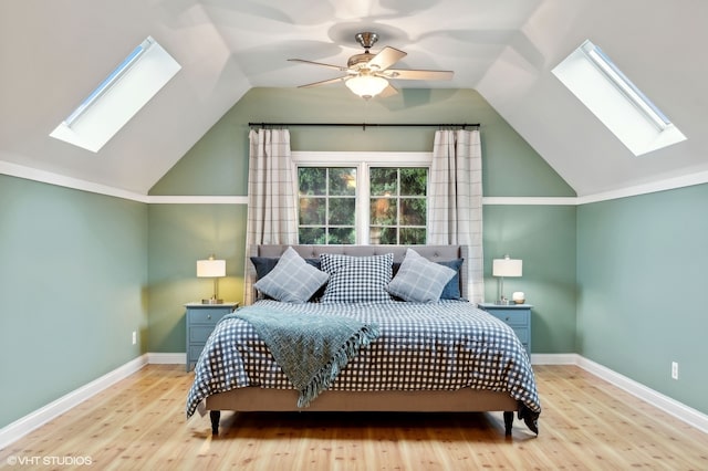 bedroom featuring light wood-type flooring, vaulted ceiling with skylight, and ceiling fan