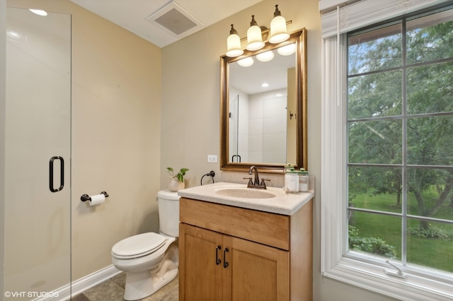 bathroom with a shower with door, vanity, toilet, and a wealth of natural light