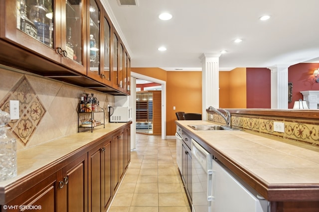 kitchen with tile counters, sink, decorative backsplash, and decorative columns