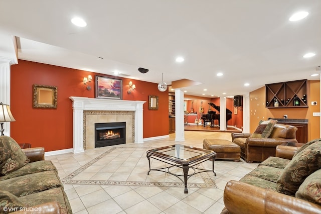 living room with a tiled fireplace, light tile patterned floors, and decorative columns