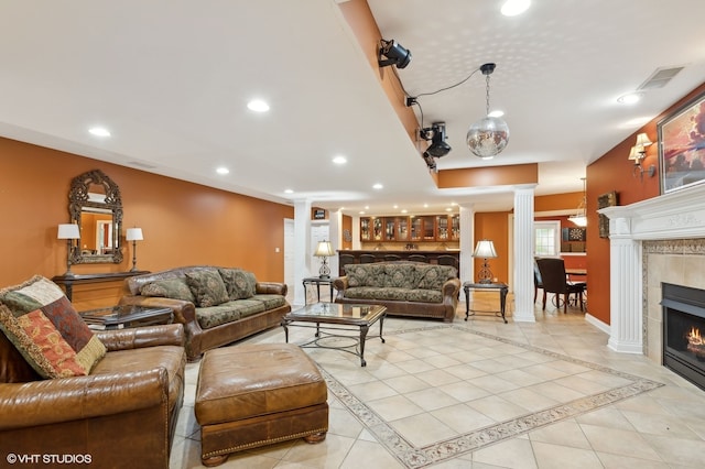 living room featuring light tile patterned floors, decorative columns, and a fireplace