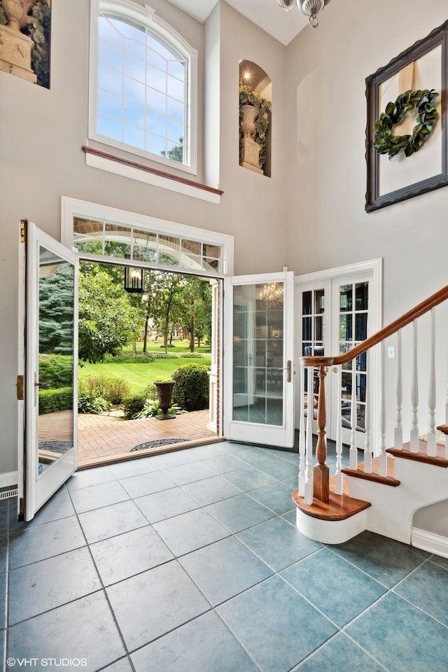 entrance foyer with a towering ceiling, french doors, and tile patterned floors