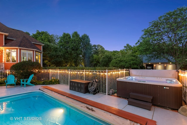 pool at dusk featuring a patio and a hot tub