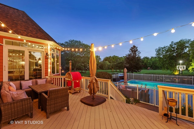 deck at dusk with a fenced in pool and an outdoor hangout area