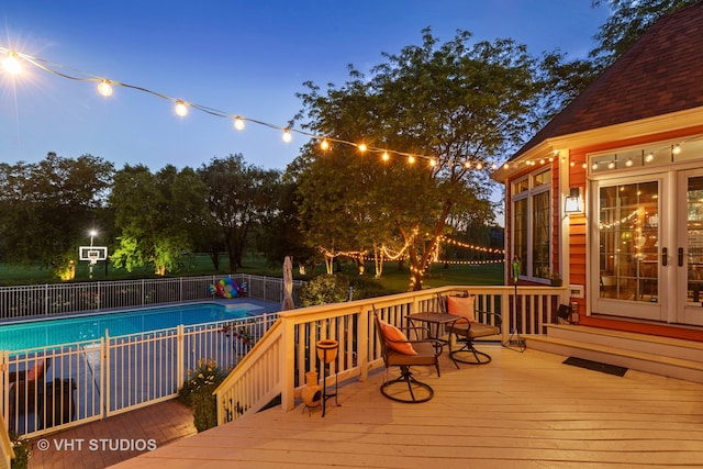 deck at dusk featuring a fenced in pool