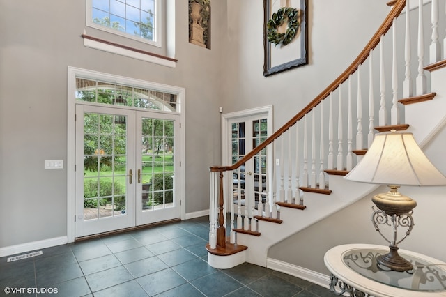 tiled foyer with plenty of natural light, a towering ceiling, and french doors