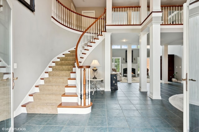 interior space featuring tile patterned flooring, a towering ceiling, and ornate columns