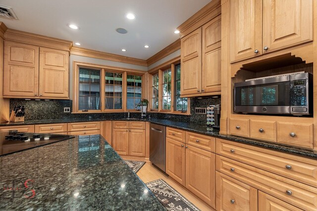 kitchen featuring crown molding, dark stone counters, tasteful backsplash, and stainless steel appliances