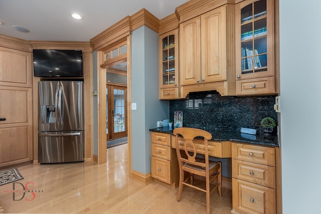 kitchen featuring stainless steel refrigerator with ice dispenser, dark stone counters, light hardwood / wood-style floors, tasteful backsplash, and built in desk