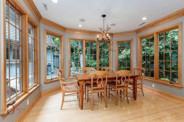 dining space featuring light hardwood / wood-style floors, ornamental molding, and a chandelier