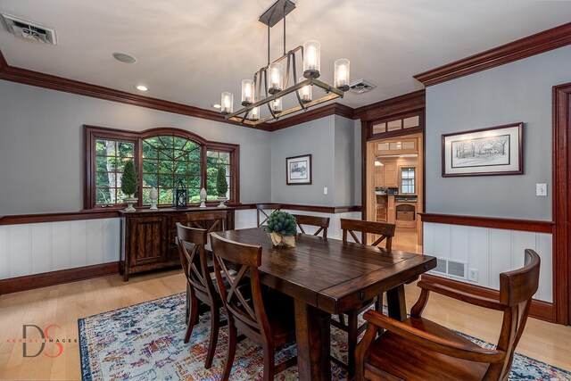 dining room with light hardwood / wood-style flooring, crown molding, and a chandelier