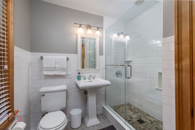 bathroom with tile walls, toilet, tile floors, sink, and walk in shower