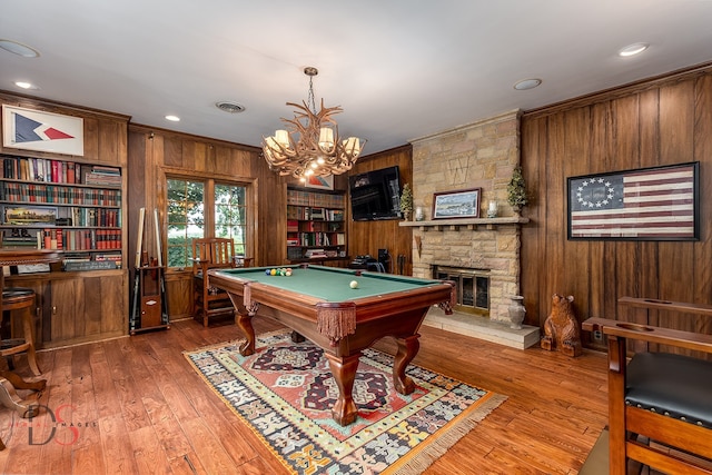 recreation room with hardwood / wood-style floors, a fireplace, billiards, wood walls, and a chandelier