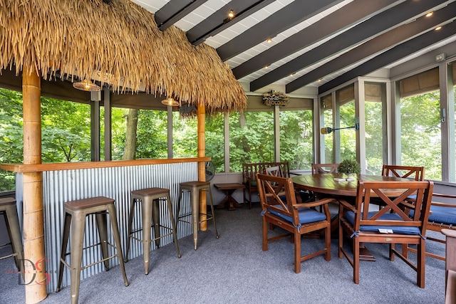 sunroom / solarium featuring lofted ceiling with beams