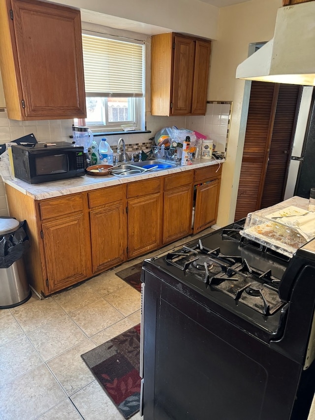 kitchen featuring black appliances, ventilation hood, sink, light tile patterned floors, and tasteful backsplash