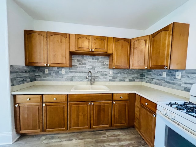 kitchen featuring sink, white gas range oven, hardwood / wood-style flooring, and tasteful backsplash