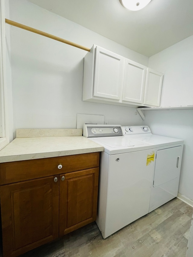 washroom with cabinets, light wood-type flooring, and washer and clothes dryer