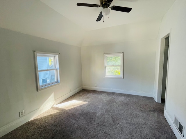 carpeted empty room featuring ceiling fan, lofted ceiling, and plenty of natural light