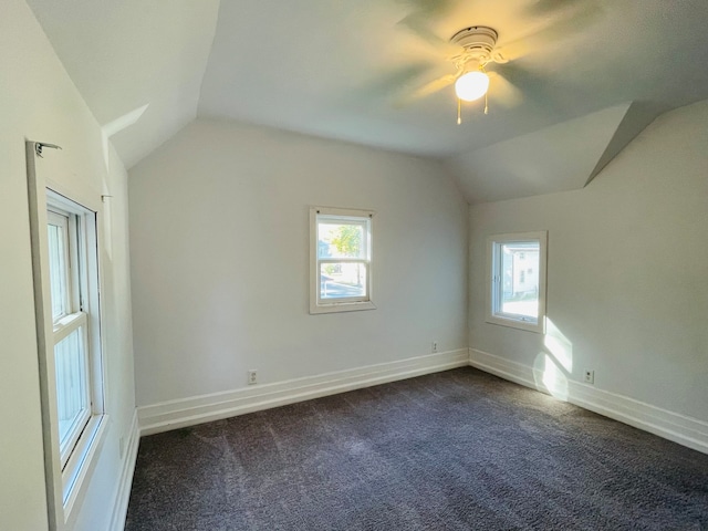 additional living space with a healthy amount of sunlight, lofted ceiling, and dark colored carpet