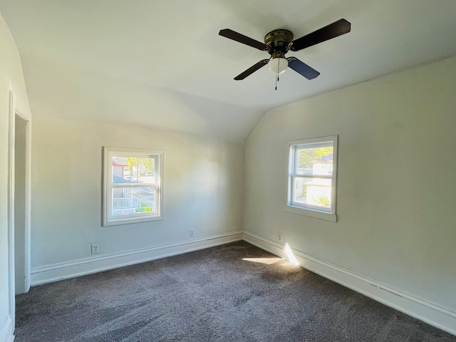 spare room featuring lofted ceiling, ceiling fan, and dark colored carpet