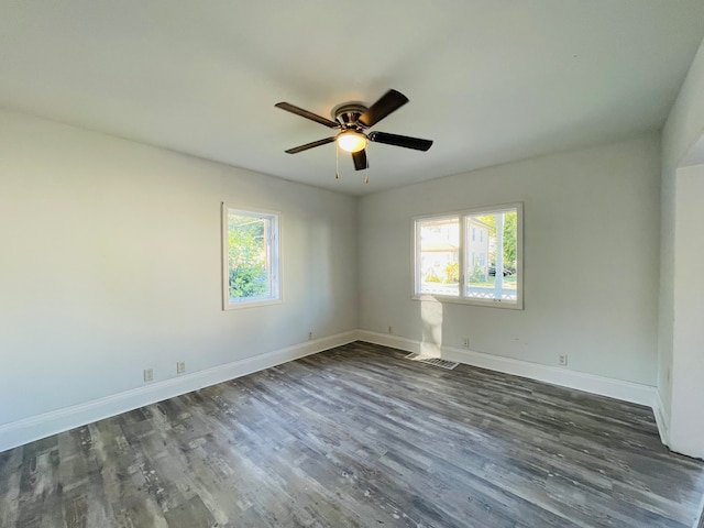 unfurnished room featuring dark wood-type flooring, a healthy amount of sunlight, and ceiling fan