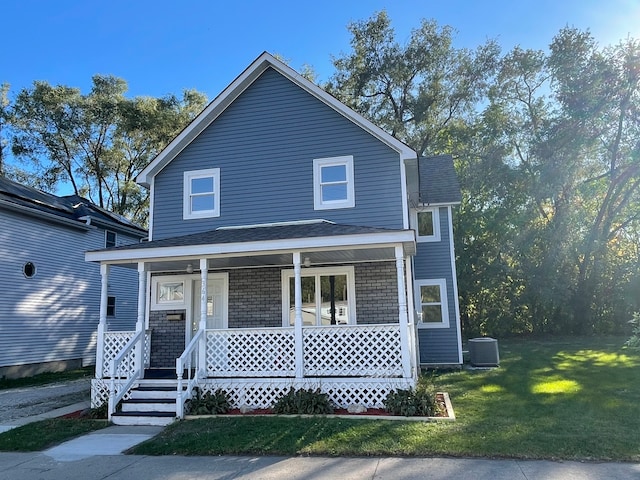 view of front of property featuring cooling unit, a front lawn, and covered porch