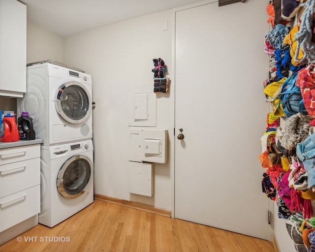 laundry room featuring cabinets, light hardwood / wood-style floors, and stacked washer / drying machine