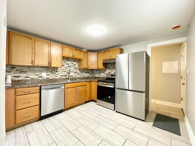 kitchen featuring sink, appliances with stainless steel finishes, dark stone countertops, and tasteful backsplash