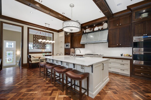 kitchen featuring decorative light fixtures, stainless steel appliances, plenty of natural light, and an island with sink