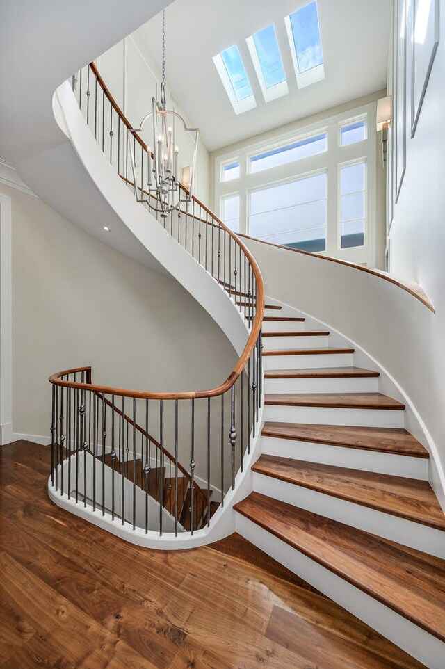 stairs with a notable chandelier, hardwood / wood-style flooring, and a skylight